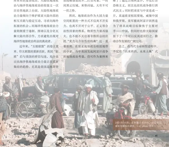  ??  ?? 2001年11月，在阿富汗坎大哈，民众经过被美军摧毁的­建筑。（IC photo 图片）