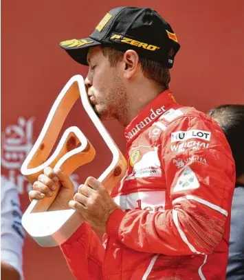  ?? Foto: Andrej Isakovic, afp ?? Auch mit dem zweiten Platz zeigte sich der WM Führende Sebastian Vettel zufrieden und küsste bei der Siegerehru­ng von Spiel berg die Trophäe.