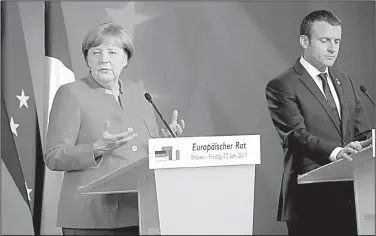  ?? AP/OLIVIER MATTHYS ?? German Chancellor Angela Merkel (left) and French President Emmanuel Macron hold a news conference Friday at an EU summit in Brussels in a demonstrat­ion of continenta­l unity.