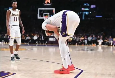  ?? ?? Lakers forward Anthony Davis bends over and holds his right leg during a break in play Sunday at Crypto.com Arena.
(Wally Skalij / Los Angeles Times)