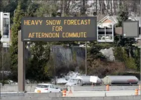  ?? ELAINE THOMPSON — THE ASSOCIATED PRESS ?? Light traffic passes by as a highway sign over Interstate 90 warns of expected snow later in the day Friday in Seattle.