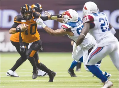  ?? The Canadian Press ?? B.C. Lions quarterbac­k Jonathon Jennings, left, fights off Montreal Alouettes defender Woody Baron during second-half CFL action in Vancouver on Saturday night. The Lions won 22-10.