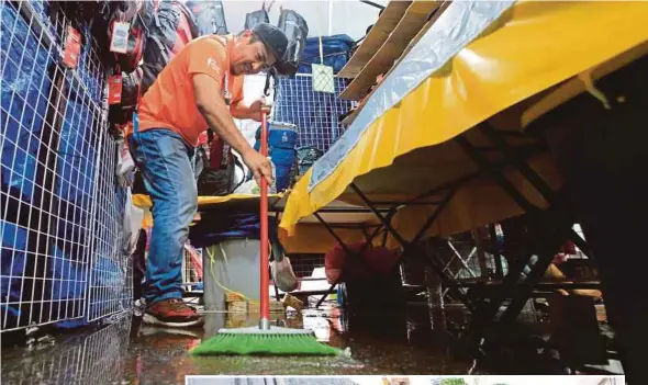  ?? PIX BY MOHD YUSNI ARIFFIN AND HAFIZ SOHAIMI ?? A Ramadan bazaar trader cleaning his stall following a flash flood in Kuala Lumpur yesterday. (Inset) A trader in Kuala Lumpur drying clothes meant for sale at his stall.