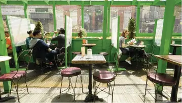  ?? MARY ALTAFFER AP ?? Lunch-hour customers still practice social distancing at an outdoor seating area of a restaurant in the Greenwich Village neighborho­od of Manhattan in New York City on Tuesday. Teams of experts are projecting COVID-19’s toll on the U.S. will fall sharply by the end of July, according to research released by the government Wednesday.