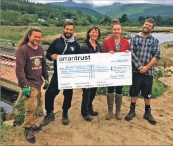  ??  ?? Receiving a cheque from the Arran Trust is the coastal way path group in Brodick: left to right, Scott Murdoch, Xabi Landaberea, Rachel Sedman, Leah Hughes, from the trust, and Iain MacDonald.