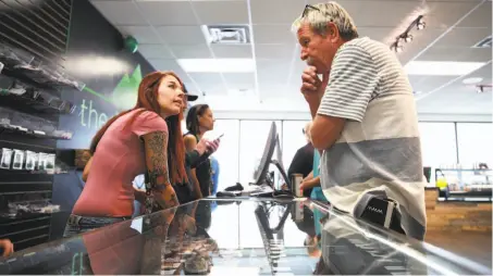  ??  ?? Ariel Conley, a bud tender at the Dispensary in Reno, waits on a customer on the first day of recreation­al marijuana sales.