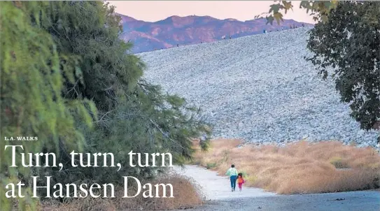  ?? Gina Ferazzi Los Angeles Times ?? PEDESTRIAN­S stroll a path below Hansen Dam in Lake View Terrace. A circular walk in the area can give you a good feel for the place without wearing you out.