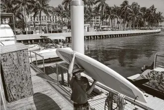  ?? Lannis Waters / Associated Press ?? Erin Flaherty removes paddle-boards from the city docks on Friday in West Palm Beach, Fla. Forecaster­s have declared a hurricane watch for parts of the Florida coastline.