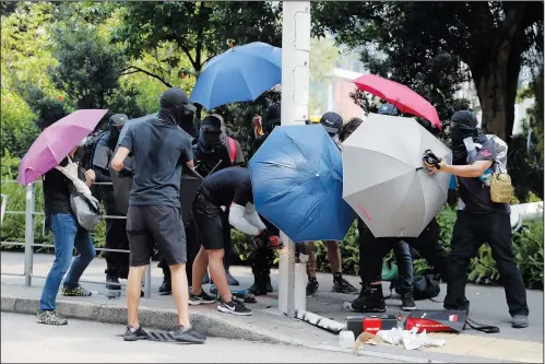  ?? (File Photo/ap/kin Cheung) ?? Demonstrat­ors use umbrellas Aug. 24, 2019, to shield themselves from view while they try to cut down a smart lamppost during a protest in Hong Kong. Stories circulatin­g online incorrectl­y claim a video shows people in Hong Kong “rebelling against the COVID police state by cutting down and destroying security cameras.”