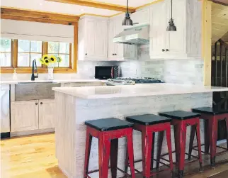  ?? PHOTOS COURTESY OF REBECCA MITCHELL INTERIORS ?? Laminate kitchen cabinetry has the look of weathered wood and complement­s the rustic feel of this chalet in the Laurentian­s.