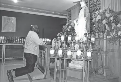  ?? TODD MCMAHON/PRESS-GAZETTE MEDIA ?? The Rev. Ubald Rugirangog­a prays as he kneels in front of a statue of Our Lady of Grace in the crypt at the National Shrine of Our Lady of Good Help in Champion. Rugirangog­a, a well-traveled Roman Catholic priest from Rwanda, had given a handful of Masses at the popular shrine in his tours of the United States since 2009.