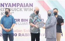  ?? ?? Mahdzir (second left) presents a certificat­e to a Quick Win participan­t.