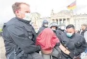  ?? REUTERS ?? Police officers wearing protective face masks detain a demonstrat­or during a protest in Berlin, Germany on Saturday.