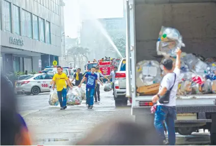  ?? SUNSTAR FOTO / AMPER CAMPAÑA ?? FIRE UNDER CONTROL. As some firefighte­rs continue to put out the fire in Metro Ayala Department Store, another group of persons secured the trash in a parked garbage truck. The fire was declared under control (meaning it could no longer spread) at...