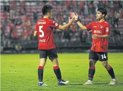  ??  ?? THE KIRINS’ SAVIOUR: Muang Thong’s Suporn Pinakataph­o, left, celebrates his equaliser against Buriram United with teammate Chatmongko­l Thongkiri.