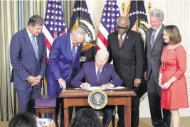 ?? SUSAN WALSH AP ?? President Joe Biden signs the Inflation Reduction Act in August, as Sen. Joe Manchin, D-W.Va., Senate Majority Leader Chuck Schumer of N.Y., House Majority Whip Rep. James Clyburn, D-S.C., Rep. Frank Pallone, D-N.J., and Rep. Kathy Castor, D-Fla., watch.