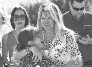  ?? JOEL AUERBACH/ASSOCIATED PRESS FILE PHOTO ?? Mechelle Boyle, right, embraces Cathi Rush as they wait for news after reports of a shooting at Marjory Stoneman Douglas High School in Parkland, Fla. The image, from Feb. 14, 2018, became emblematic of the Parkland school massacre: two terrified mothers waiting outside the school. A year after the shooting, the two women are no longer in contact, disagreein­g over gun control and politics.