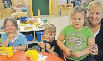  ??  ?? Cass Roach, director of the Jewels and Gems Day Care, sat down with children, from left, Jordan Mauger, Dean Smith and Sophie Pilling, while they ate their lunch, Tuesday.