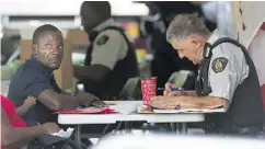  ??  ?? An asylum seeker is processed on Friday by RCMP officers in Hemmingfor­d, Que. There has been a spike in people trying to cross into Quebec in recent weeks.