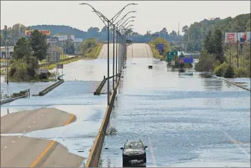  ?? Gerry Broome Associated Press ?? VEHICLES SIT on a closed section of Interstate 95 in Lumberton, N.C., where the Lumber River overf lowed after Hurricane Florence, which turned the Carolinas into a maze of flooded towns and highways.