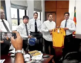  ??  ?? Sports Minister Harin Fernando is presented with a national jersey by FFSL President Anura de Silva. The Minister would probably consider wearing it, with the amount of troubles he has.