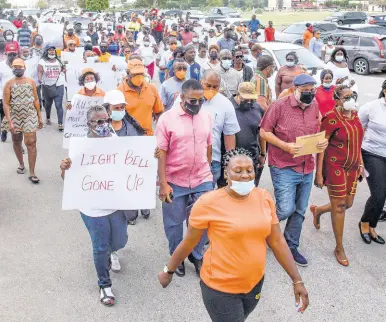  ?? NICHOLAS NUNES/ PHOTOGRAPH­ER ?? Followed by protesters, Mark Golding (in blue Kangol cap), leader of the Opposition, marches with a copy of a draft ministeria­l order to the Ministry of Finance and the Public Service Monday.