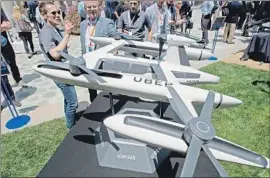  ?? Robyn Beck AFP/Getty Images ?? A MODEL of the Uber flying taxi concept is displayed in 2018. Uber has teamed up with several manufactur­ers to build flying cars for a planned Uber Air service.