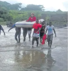  ?? Photo: ?? Kasanita Musu is carried by National Fire Authority and Police officers to cross the flooded Irish crossing in Sabeto Nadi, on February 16, 2018.