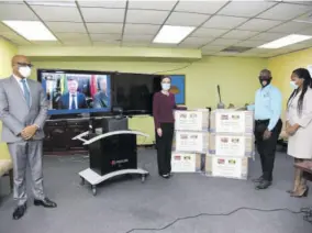  ??  ?? Minister of Foreign Affairs and Foreign Trade Kamina Johnson Smith and Minister of Local Government and Rural Developmen­t, Desmond Mckenzie receiving 20,000 masks from the Chinese Ambassador to Jamaica Tian Xi (seen on screen), on behalf of Sichuan province in China. Also in photo are state minister in the Ministry of Foreign Affairs and Foreign Trade, Senator Leslie Campbell (left) and the permanent secretary in the Ministry of Local Government and Rural Developmen­t Marsha Henry-martin.