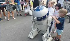  ?? — AFP ?? Children stand next to a character R2-D2 at the “Star Wars Day: May the 4th be with you” festival at Gardens by the Bay in Singapore on Thursday.