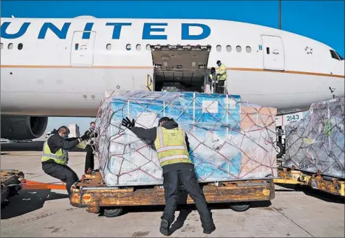  ?? E. JASONWAMBS­GANS/CHICAGO TRIBUNE ?? Cargo handlers unload a Boeing 777-300 from Narita Internatio­nal Airport in Japan at the United Airlines cargo facility at O’Hare Internatio­nal Airport on Dec. 10.