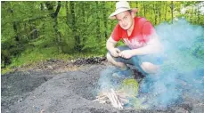  ?? FOTO: HEINZ THUMM ?? Max Geiselhart entzündet mit Holzspänen die Holzkohle im Schacht, die dann gemächlich von oben nach unten verglüht.