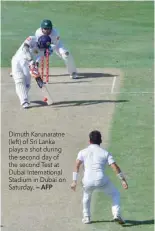  ?? — AFP ?? Dimuth Karunaratn­e (left) of Sri Lanka plays a shot during the second day of the second Test at Dubai Internatio­nal Stadium in Dubai on Saturday.