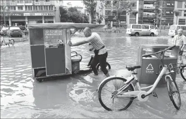  ?? ZHANG LANG / CHINA NEWS SERVICE ?? A man pushes his vehicle in a flooded street in Chengdu, Sichuan province, on Thursday.