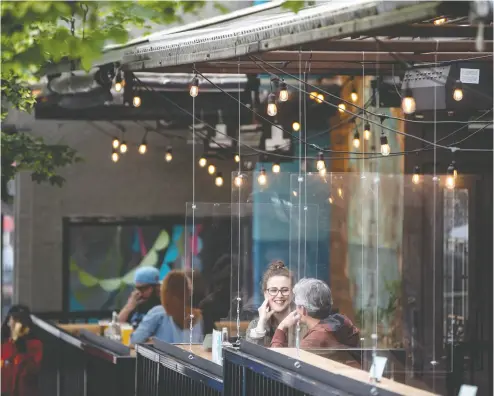  ?? DARRYL DYCK / THE CANADIAN PRESS ?? Patrons sit between Plexiglas barriers on the patio of a restaurant and bar in Vancouver last week.