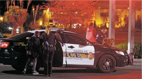  ?? LUIS SÁNCHEZ SATURNO/THE NEW MEXICAN ?? Sgt. Bryan Martinez, right, fills out paperwork while Officer Jacqueline Rowell arrests a woman suspected of shopliftin­g and possession of drug parapherna­lia Thursday outside Walgreens on Cerrillos Road. Outgoing Chief Patrick Gallagher says the...