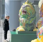  ??  ?? A passerby reads an introducti­on on ‘Stephen’, one of the two lions in rainbow colours to show support for the LGBT community being displayed at HSBC’s main branch in Hong Kong.