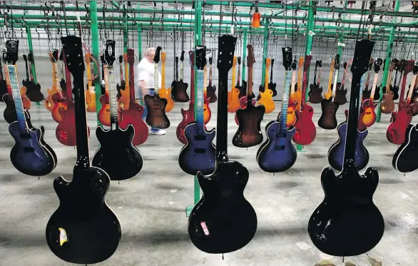  ?? JEFF ADKINS/BLOOMBERG FILES ?? Painted guitars hang to dry after being lacquered at the Gibson. factory in Nashville, Tenn. With the noteholder agreement, Gibson aims to become a more nimble, reorganize­d company that will be able to address its problems and return focus to the core...