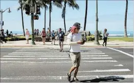  ?? CALEB JONES/AP ?? A man does what’s now a Honolulu no-no — looks at his phone as he crosses a street.