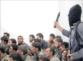  ?? Raqqah Media Center ?? A FIGHTER with Islamic State is shown with captured government troops after the battle for Tabqa air base in August 2014. Hundreds of soldiers were killed.