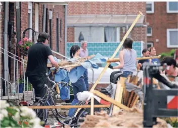  ?? FOTO: KAISER/DPA ?? Betroffene und Nachbarn räumen die auf der Straße liegenden Trümmer weg. Am Vorabend hat es in der Bocholter Heroldstra­ße einen Tornado gegeben.