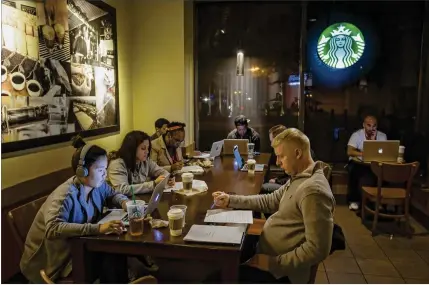  ?? ALI ASAEI / THE NEW YORK TIMES ?? Patrons sit below the Starbucks logo in a shop in New York. Many participan­ts in a recent study failed to re-create famous logos from brands such as Apple and Starbucks. But some experts say that shouldn’t worry companies.