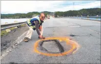  ?? CP PHOTO ?? Ernest Barnes, Summerford’s “Pothole Man,” has made it his mission to mark the dangerous stretches of road along the Road to the Isles. Barnes is pictured circling a pothole along a stretch of road.