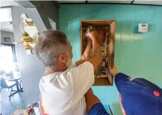  ?? Staff photo by Kelsi Brinkmeyer ?? ■ Local artist Richard Cramer and his nephew Caleb Juarez install a piece of art as a part of the new antique wall at Shorty's Donut Shop and Diner. Everything newly decorating Shorty's walls is from Cramer’s personal collection.