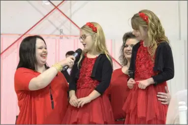  ?? The Sentinel-Record/Rebekah Hedges ?? SURVIVORS: Kaden Peebles, a 20-year-old cancer survivor, holds the microphone for twin cancer survivors Tenna and Adeline White as they share about their bouts with cancer at the Splash of Red Event at Hot Springs Memorial Field on Friday.