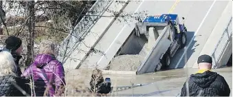  ?? DALE CARRUTHERS ?? Onlookers gather at the collapsed Imperial Road bridge in Port Bruce on Feb. 25, two days after the structure gave out amid heavy flooding as a dump truck was driving across it. Local fightfight­ers were forced to get help from their Port Stanley...