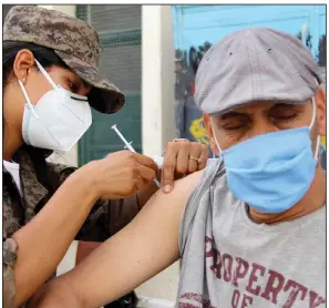  ?? (AP/Hassene Dridi) ?? A soldier administer­s the Vaxzervria covid-19 vaccine Sunday to a man at a school in Oued Ellil, Tunisia, as part of a vaccinatio­n campaign as that country faces a surge in cases. Authoritie­s aimed to vaccinate more than 1 million adults age 40 and older in one day.