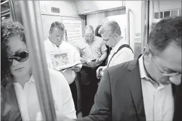  ?? MeL evANs/AssoCiATeD PRess ?? Commuters read and check their phones as they stand on a New Jersey Transit passenger train to New York from Trenton, N.J. each weekday morning, drivers heading from New Jersey into Manhattan do battle in one of the most congested metropolit­an regions...