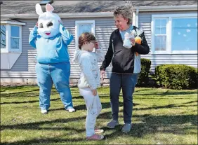  ?? SARAH GORDON/THE DAY ?? Sue McClimon thanks family friend Kaydence Day, 7, for an Easter gift Tuesday as Parks and Recreation Director Amy Brosnan, wearing a bunny mask, watches. Kids made Easter crafts through Preston Youth Services, which were then donated to area seniors. The town has been working to revive the long-dormant Youth Services Bureau with a new advisory board, activities for kids and soon a survey to residents on youth needs.