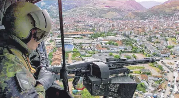  ?? FOTO: PETER KNEFFEL/DPA ?? Mit dem Bordmaschi­nengewehr sichert ein deutscher Kfor-Soldat bei einem Routineflu­g über Prizren im Kosovo den Helikopter.